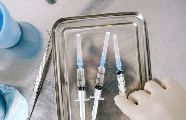 Vaccine vials and syringes on a stainless steel tray