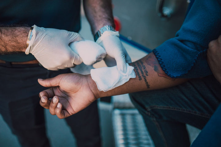 Gloved healthcare worker applying a bandage to a patient's arm