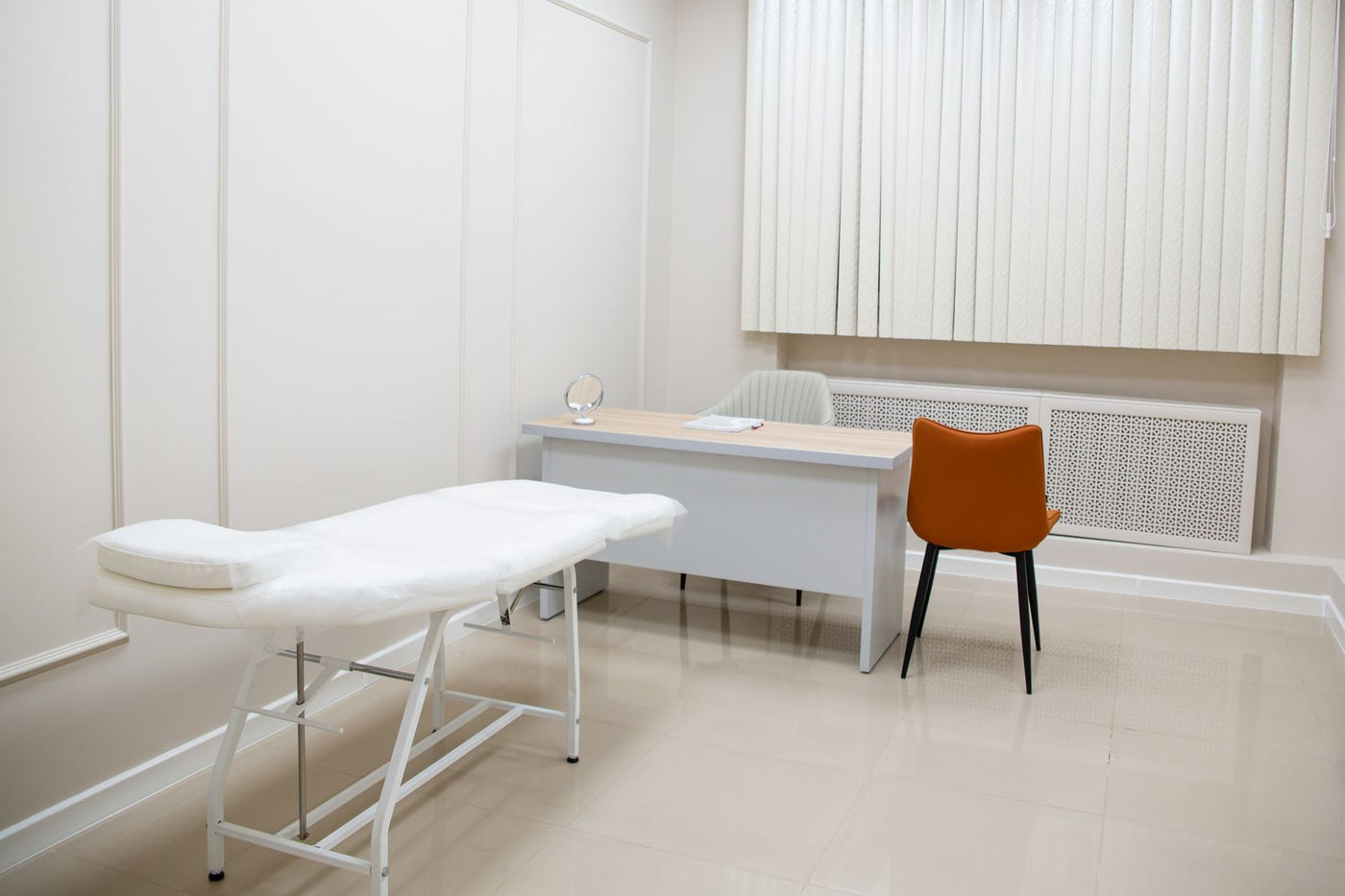 Medical examination room with exam table, desk and chairs