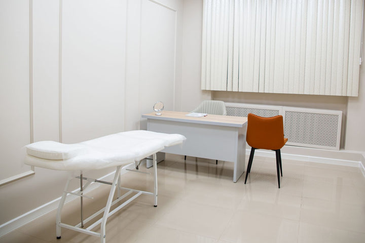 Medical examination room with exam table, desk and chairs