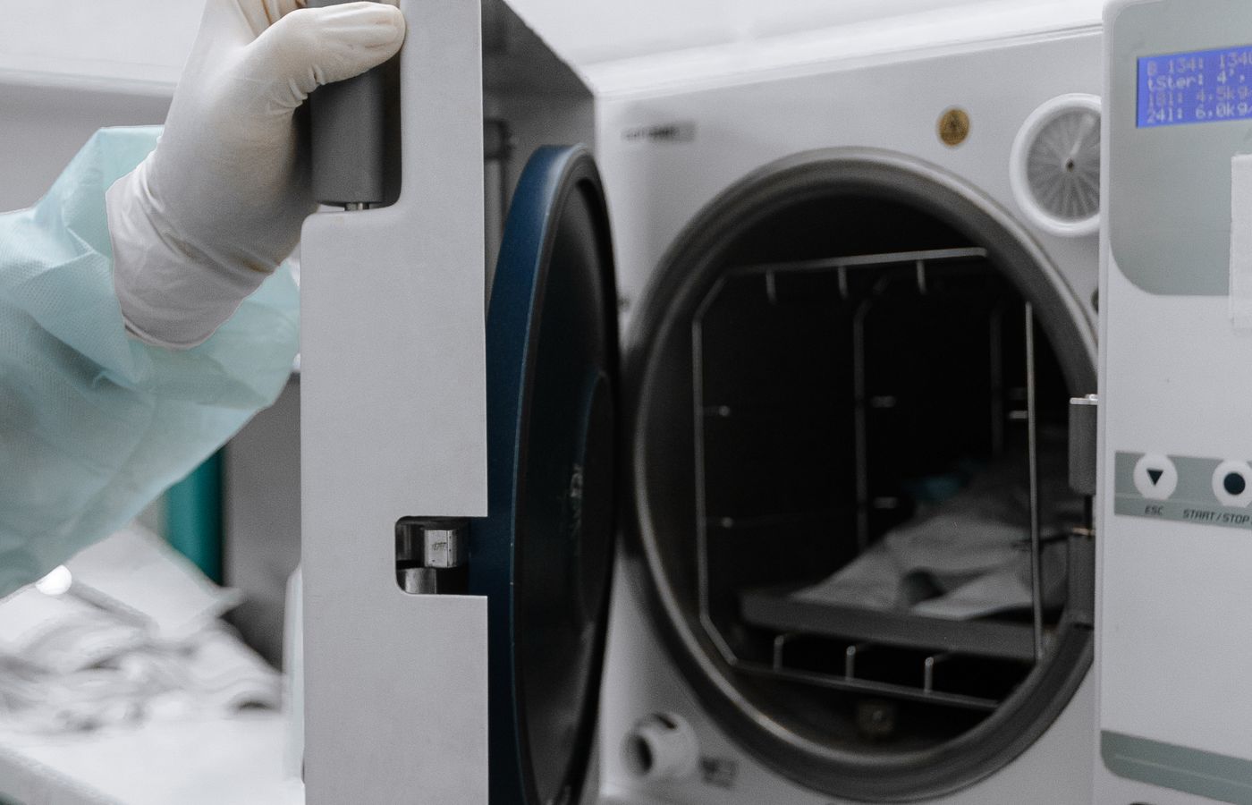 Medical autoclave sterilizer being opened by a gloved hand