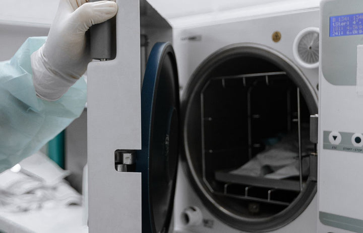 Medical autoclave sterilizer being opened by a gloved hand